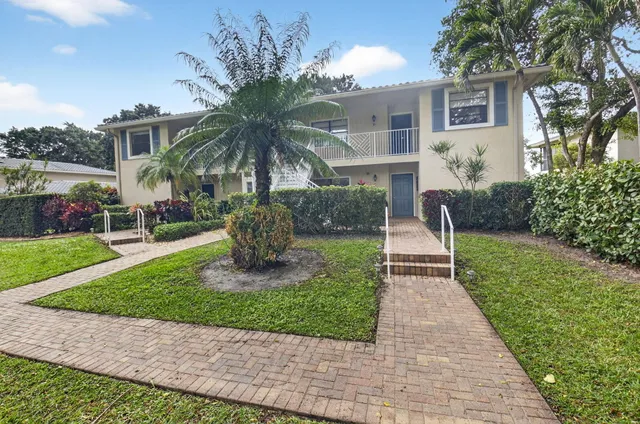 a front view of a house with a yard and potted plants