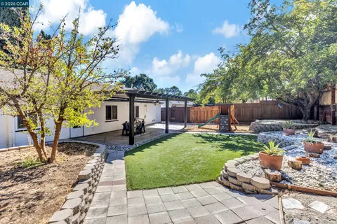 a view of a backyard with table and chairs potted plants and a large tree