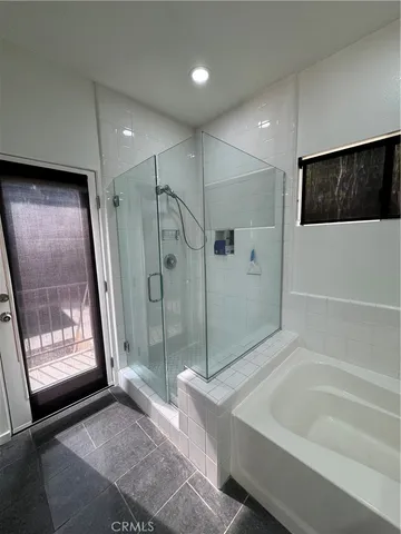 a spacious bathroom with a tub a mirror and a shower