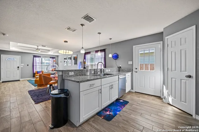 a kitchen with stainless steel appliances granite countertop a sink stove and wooden floor