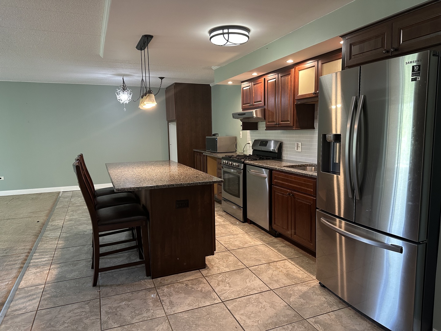 110 West Butterfield Road, Unit 402S Elmhurst, IL 60126 - Photo 3 of 17 a kitchen with stainless steel appliances a refrigerator a sink a stove a microwave and dining table
