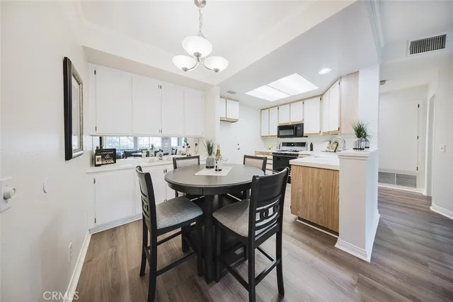 a view of a dining room and livingroom with furniture wooden floor a rug a flat screen tv a painting and a chandelier