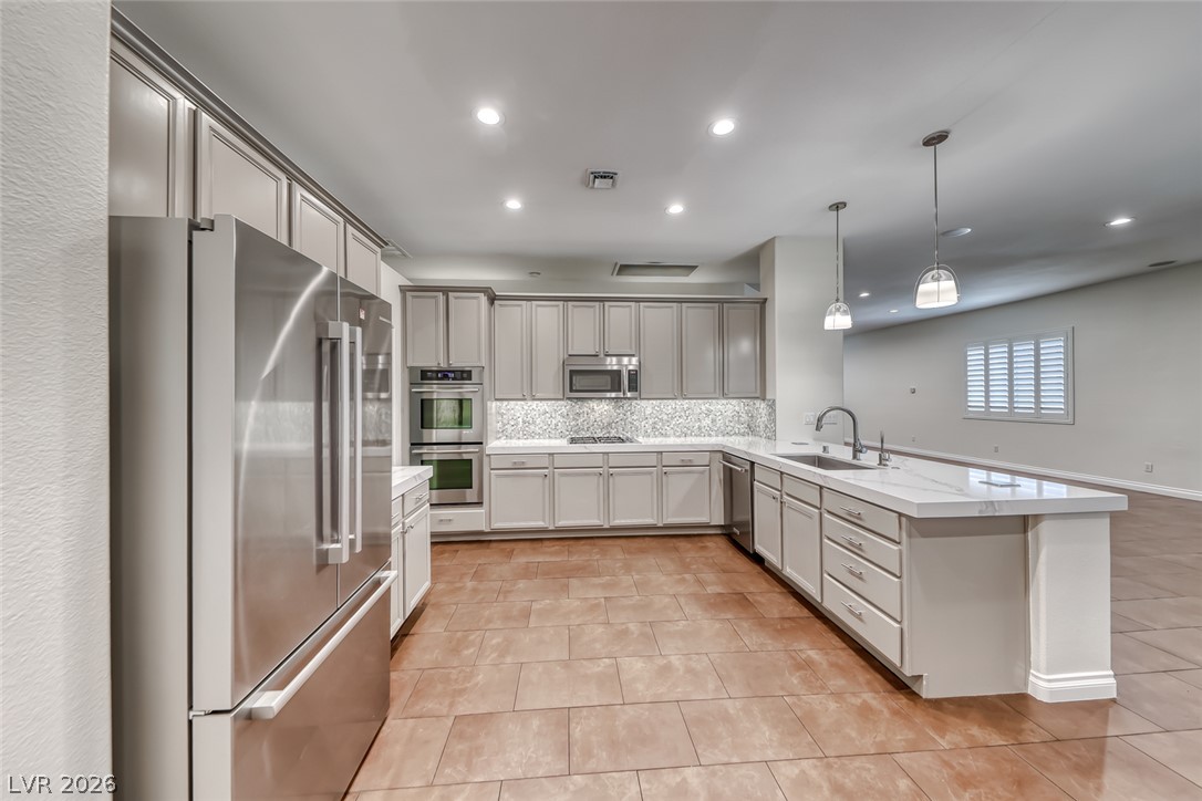 2122 Mooreview Street Henderson, NV 89012 - Photo 9 of 44 Culinary delights await in this sleek kitchen, showcasing a modern island and state-of-the-art appliances.