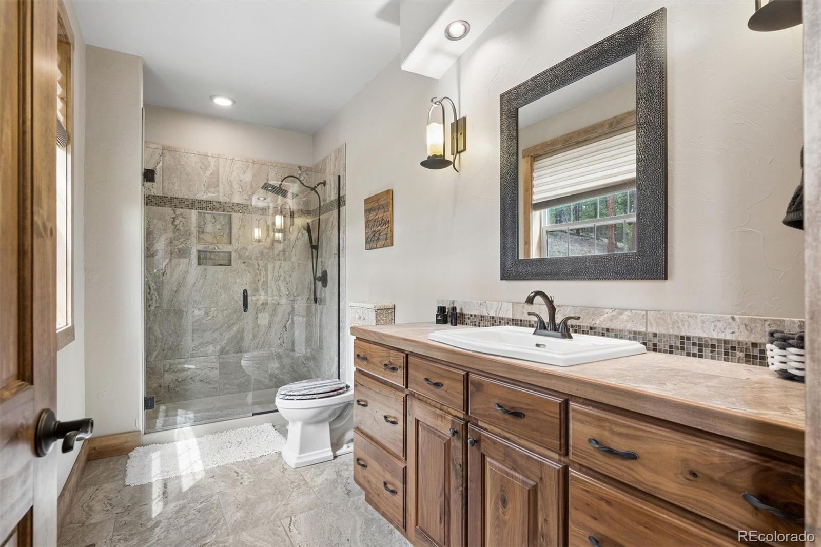 2894 County Road 43 Bailey, CO 80421 - Photo 16 of 40 a bathroom with a double vanity sink toilet mirror and shower