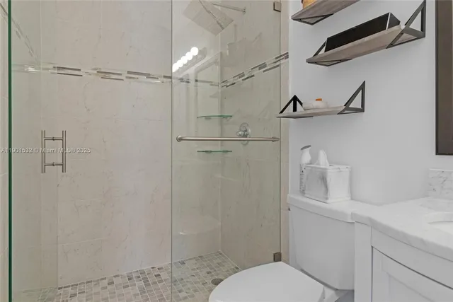 a bathroom with a granite countertop shower sink vanity and toilet