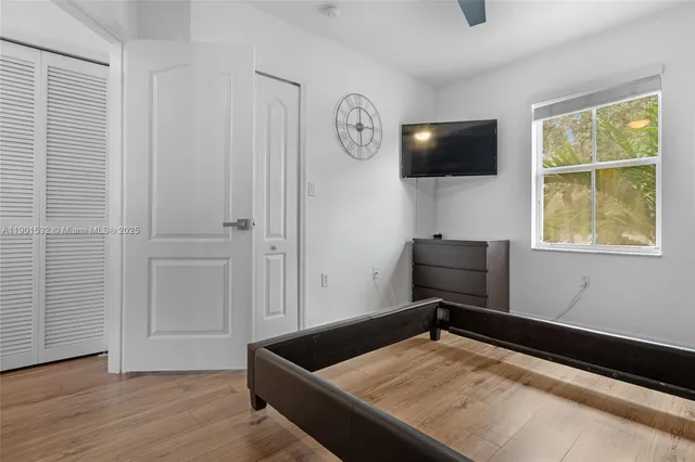 a living room with a flat screen tv on dresser and a window