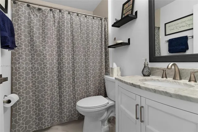 a bathroom with a granite countertop sink toilet and a mirror