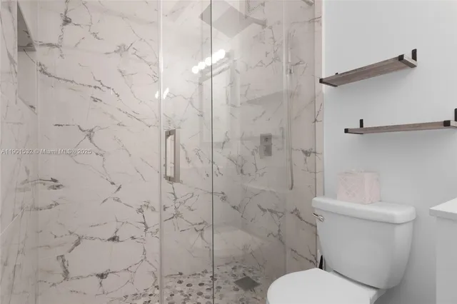 a white toilet sitting next to a shower