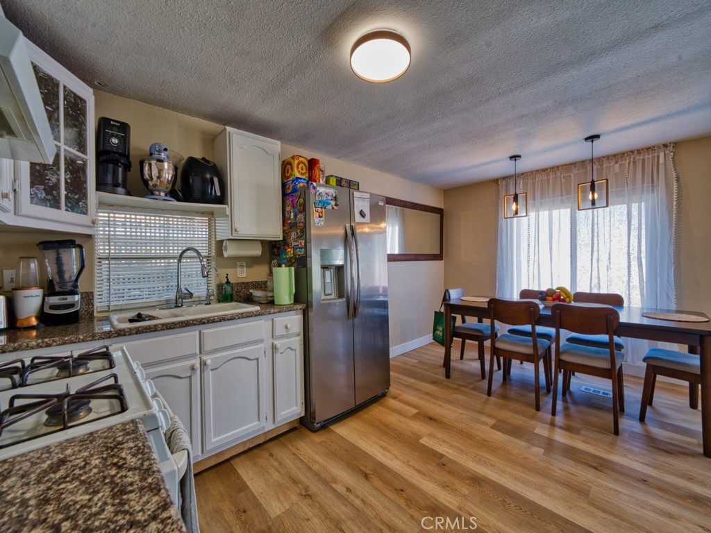 700 South Shafter, Unit 20 Shafter, CA 93263 - Photo 8 of 18 a kitchen with stainless steel appliances granite countertop a stove a refrigerator a dining table and chairs with wooden floor