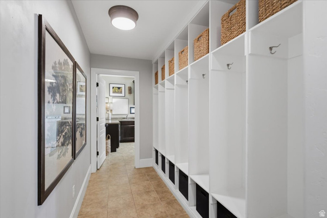 1257 Rigby Road Kaysville, UT 84037 - Photo 41 of 55 Hallway featuring built-in white lockers with storage cubbies and metal hooks, complementing the light tan tile flooring