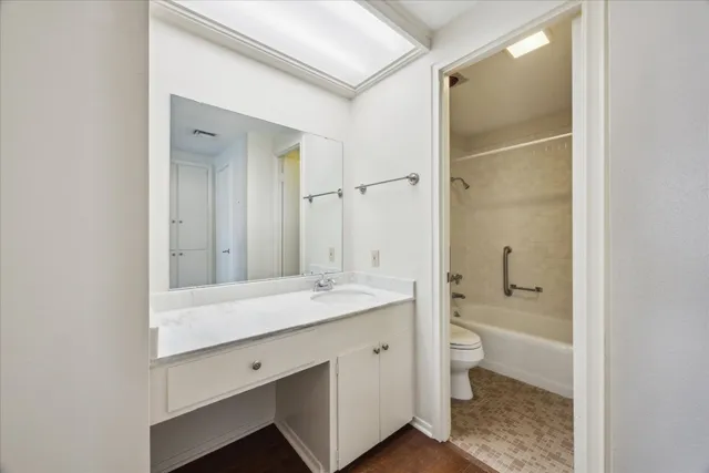 a bathroom with a granite countertop sink a toilet and shower