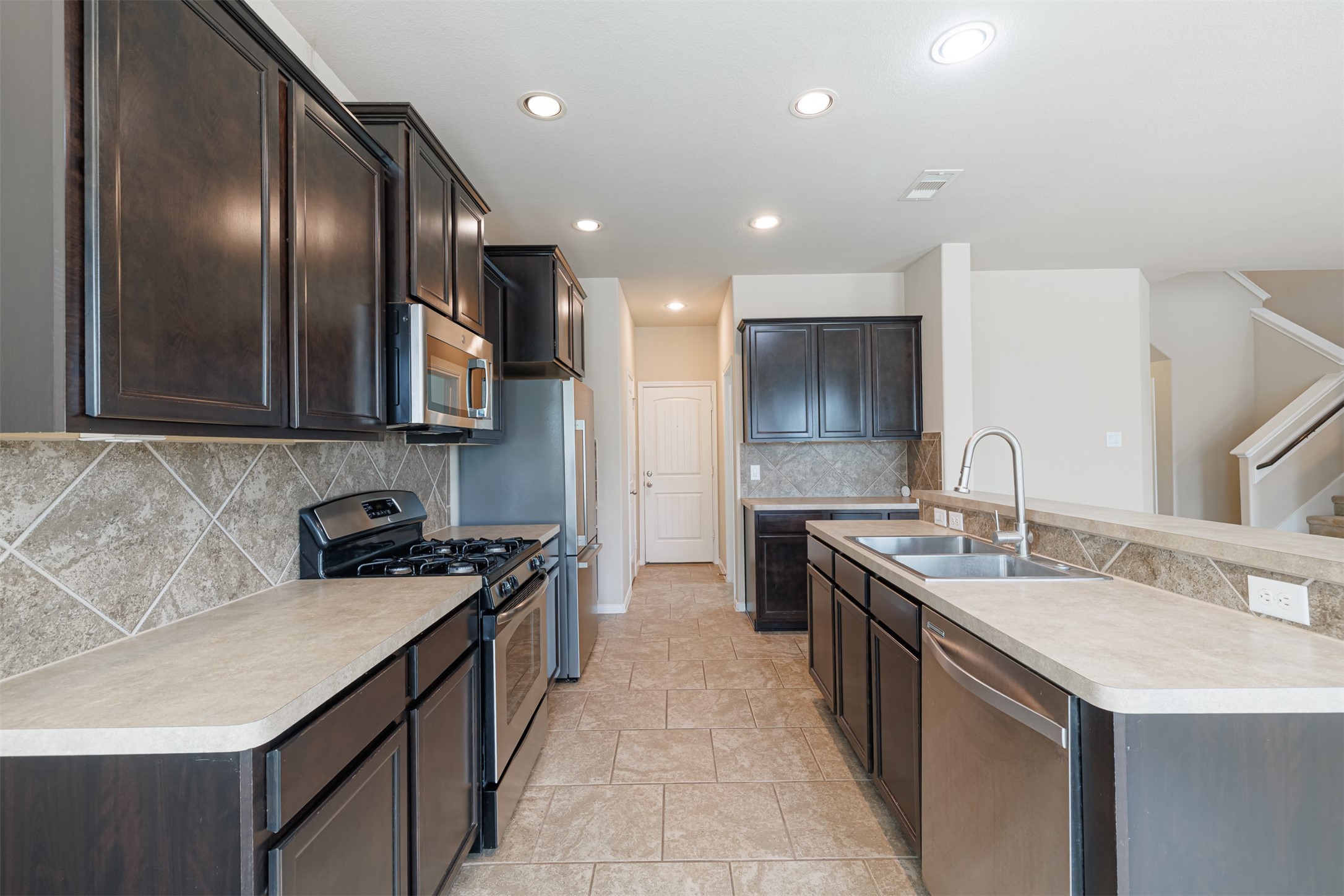 25322 Saddlebrook Ranch Drive Tomball, TX 77375 - Photo 3 of 20 a kitchen with stainless steel appliances a sink stove and cabinets