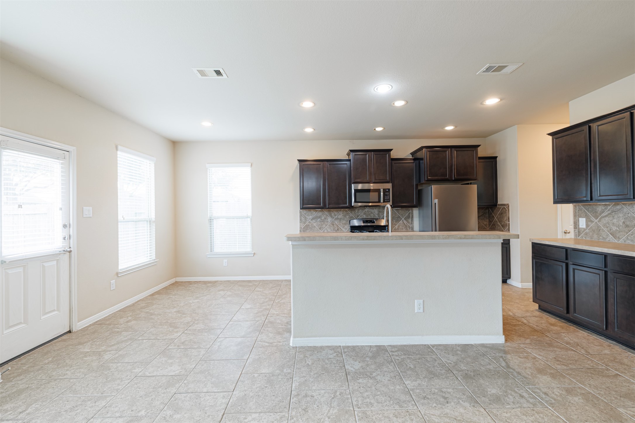 25322 Saddlebrook Ranch Drive Tomball, TX 77375 - Photo 6 of 20 a large white kitchen with kitchen island a sink a counter top space stainless steel appliances and a window