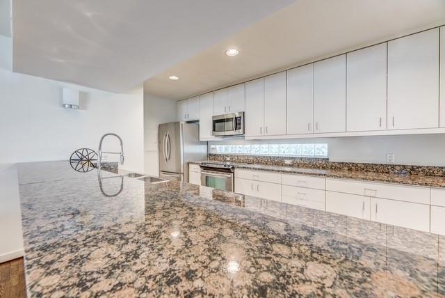4122 Travis Street, Unit 2 Dallas, TX 75204 - Photo 7 of 19 a kitchen with granite countertop a stove a sink and a microwave
