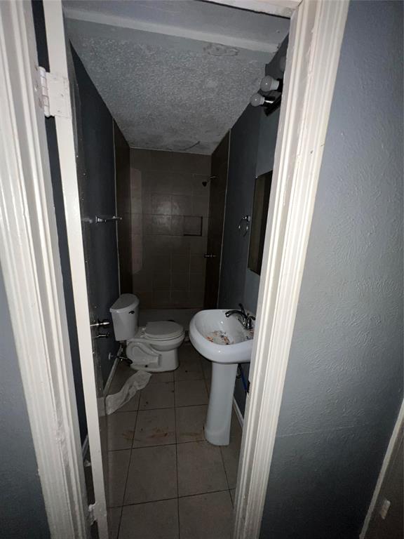 4224 Ramey Avenue Fort Worth, TX 76105 - Photo 13 of 19 Full bathroom featuring light tile patterned floors, a tile shower, a textured ceiling, and a textured wall