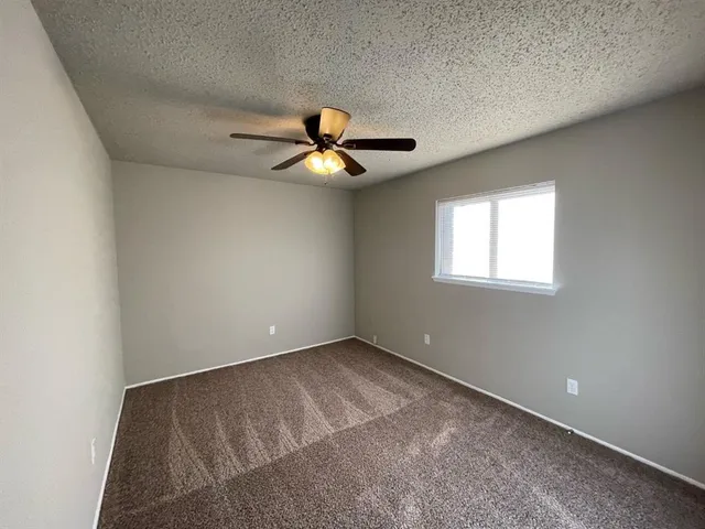 an empty room with a window and a ceiling fan