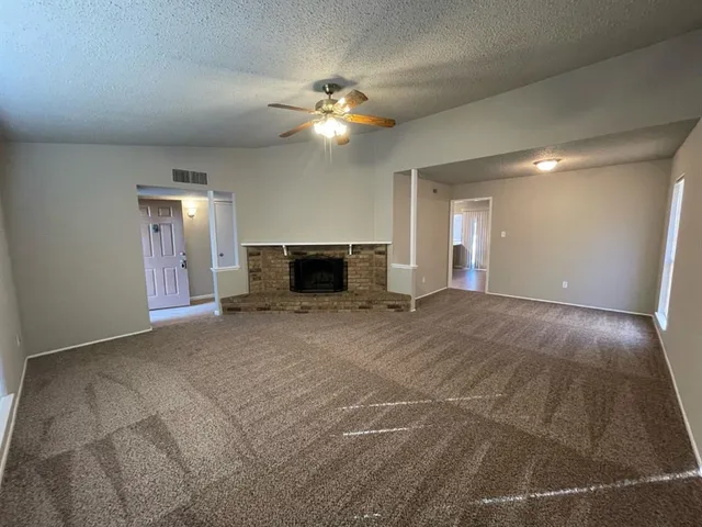 a view of a livingroom with a fireplace a ceiling fan and wooden floor