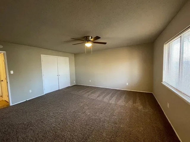 an empty room with windows and fan