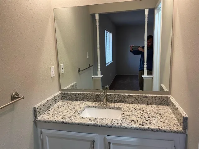 a bathroom with a granite countertop sink and a mirror