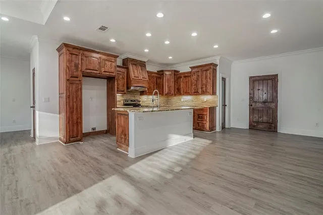 a open kitchen with kitchen island a stove a refrigerator cabinets and wooden floor
