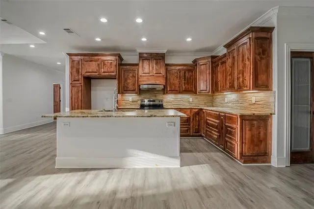 a large kitchen with stainless steel appliances granite countertop a stove a sink and a refrigerator