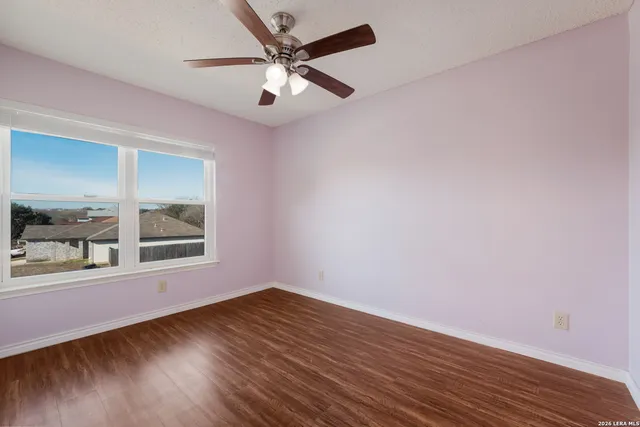 a view of empty room with wooden floor and fan