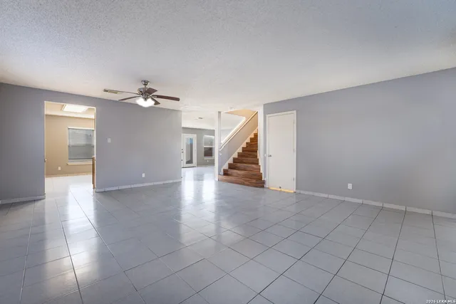 a view of an empty room with wooden floor and stairs