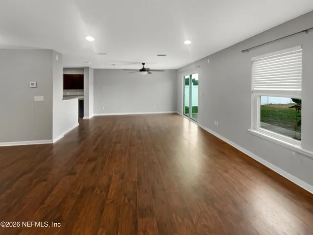 an empty room with wooden floor and windows