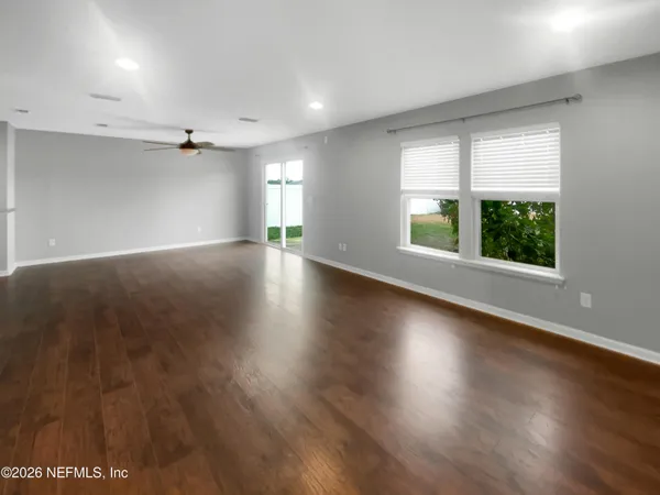 an empty room with wooden floor and windows