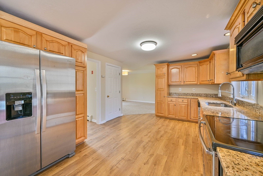 99 Smith Road Charlton, MA 01507 - Photo 16 of 37 a kitchen with stainless steel appliances granite countertop a refrigerator a stove and a sink with wooden floor