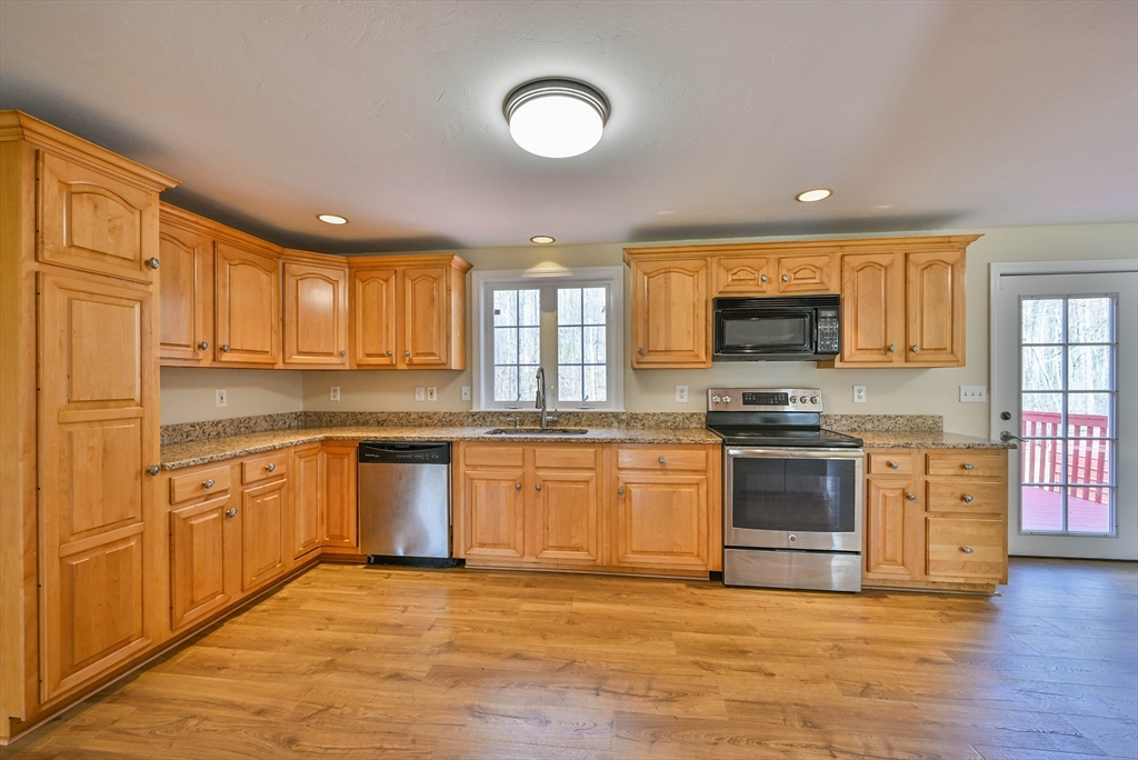99 Smith Road Charlton, MA 01507 - Photo 19 of 37 a kitchen with stainless steel appliances granite countertop a stove top oven a sink dishwasher a dining table and chairs with wooden floor