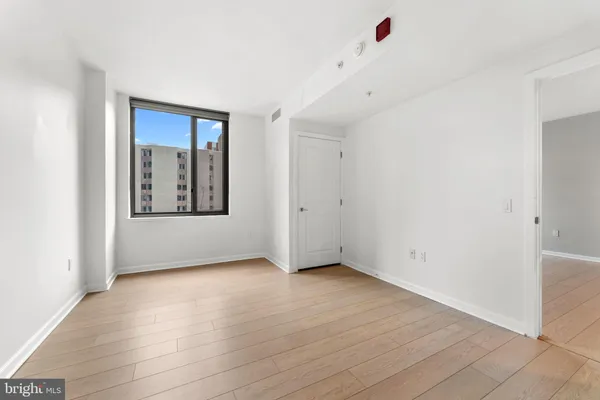 a view of an empty room with wooden floor and a window