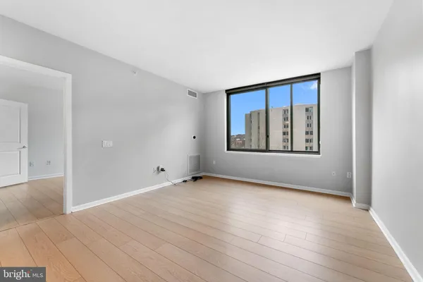 a view of an empty room with a window and wooden floor