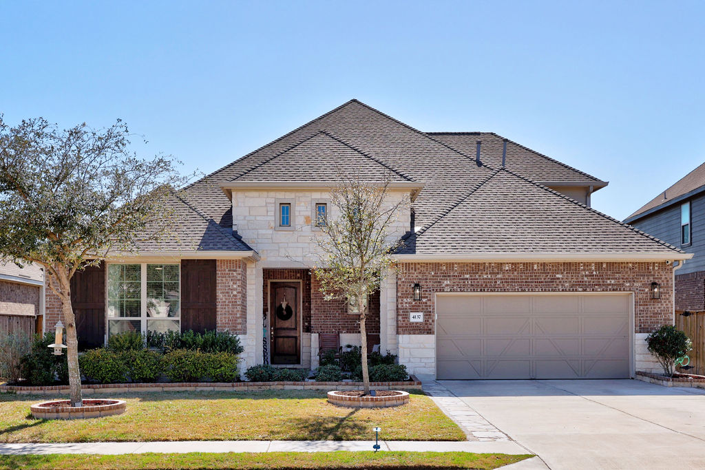 4137 Brean Down Road Pflugerville, TX 78660 - Photo 1 of 1 View of front of property featuring a garage, brick siding, a front lawn, driveway, and roof with shingles