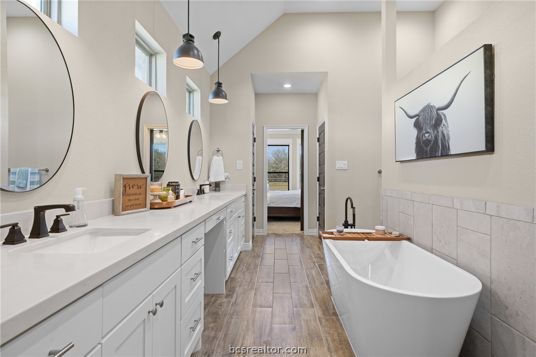 3222 Hunters Crossing Bryan, TX 77808 - Photo 23 of 44 Full bath featuring connected bathroom, tile walls, double vanity, a freestanding bath, and light wood-style tile floors