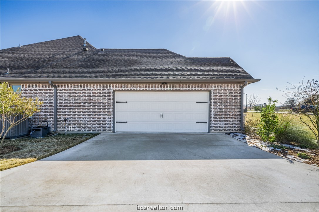3222 Hunters Crossing Bryan, TX 77808 - Photo 36 of 44 View of home's exterior featuring brick siding, driveway, roof with shingles, and an attached garage