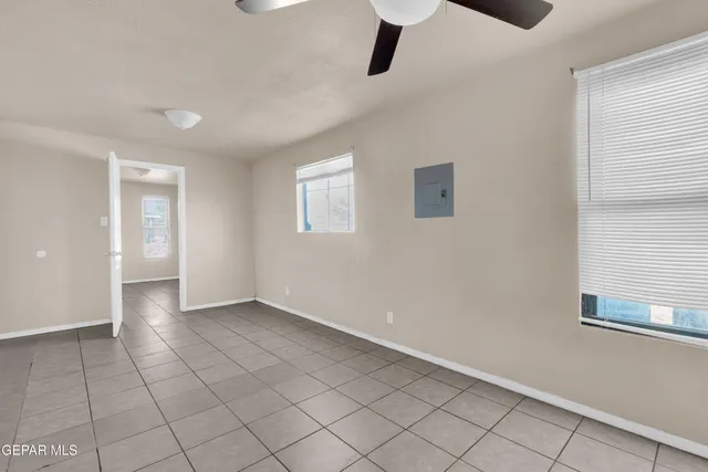 a view of an empty room with window and chandelier fan