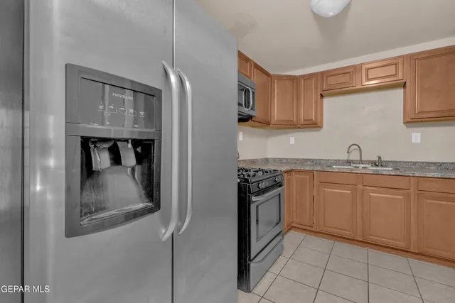 a kitchen with granite countertop a refrigerator and a sink
