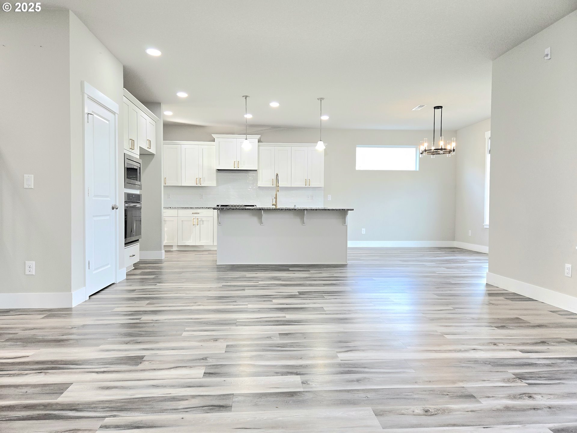 8524 North 1st Street Ridgefield, WA 98642 - Photo 12 of 48 a view of a kitchen with kitchen island a sink wooden floor and a refrigerator