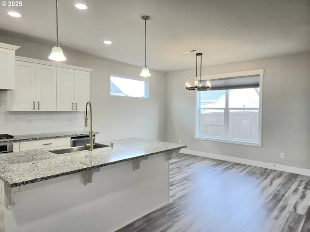 a kitchen with stainless steel appliances granite countertop a sink a window and wooden floor