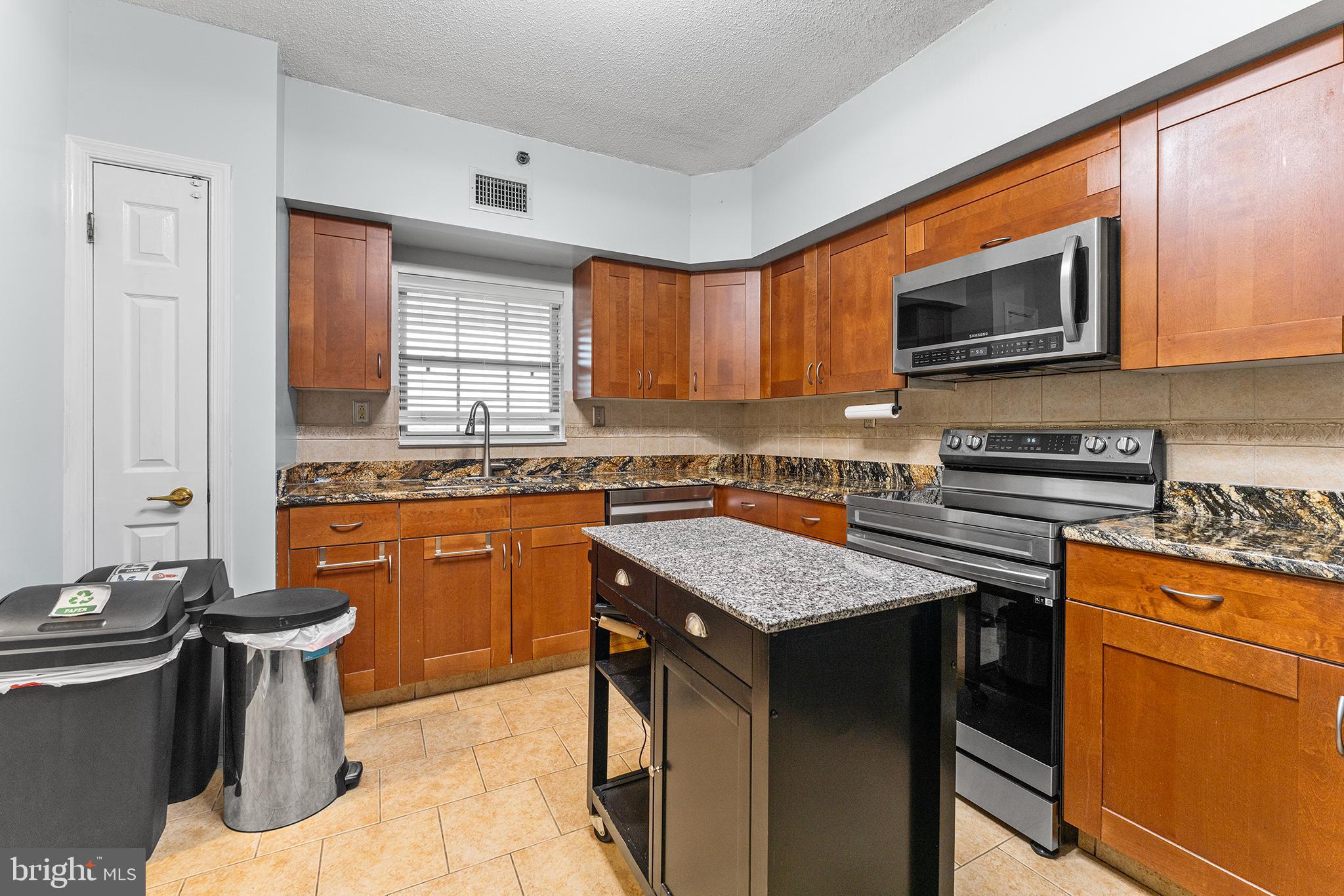 6070 Main Street Voorhees, NJ 08043 - Photo 6 of 22 a kitchen with stainless steel appliances granite countertop a stove top oven a sink dishwasher a dining table and chairs with wooden floor