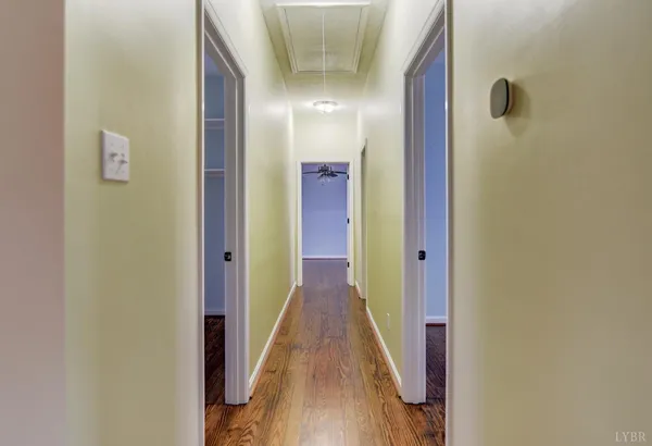 a view of a hallway with wooden floor and a bathroom