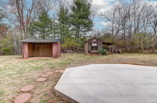 a view of a wooden house with a small yard and large trees