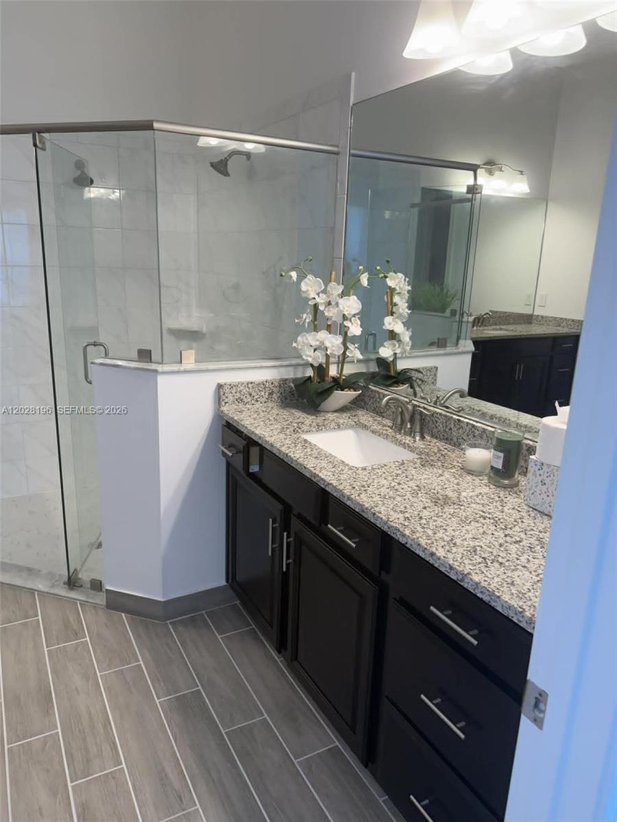 4710 Southwest Ardsley Drive Stuart, FL 34997 - Photo 4 of 7 a bathroom with a granite countertop sink a mirror and a shower