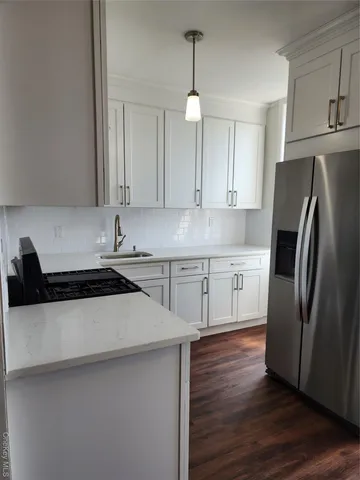 a kitchen with stainless steel appliances a refrigerator a sink a stove and white cabinets