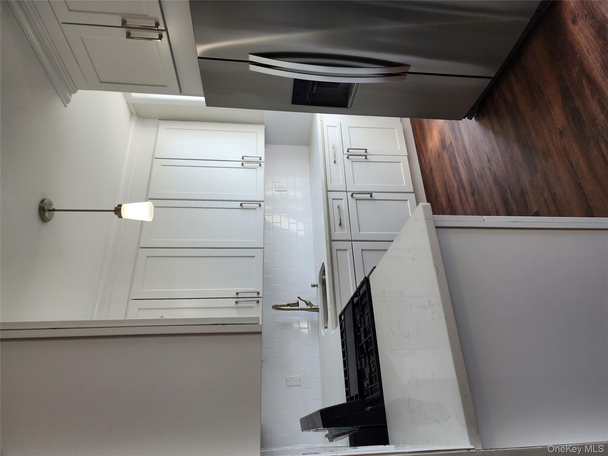 64-10 Myrtle Avenue Queens, NY 11385 - Photo 5 of 15 a kitchen with stainless steel appliances a refrigerator a sink a stove and white cabinets