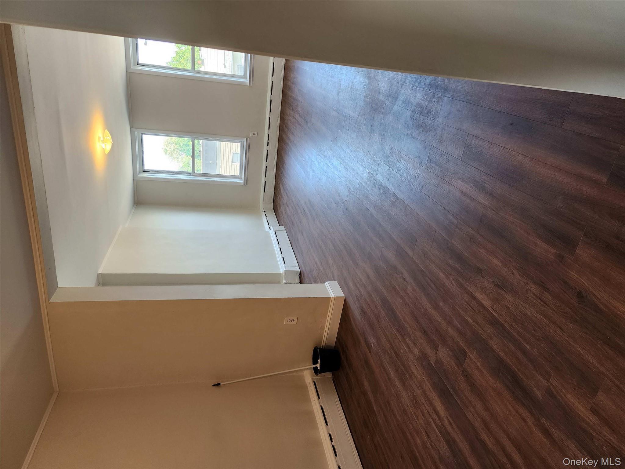 64-10 Myrtle Avenue Queens, NY 11385 - Photo 8 of 15 an empty room with wooden floor and windows