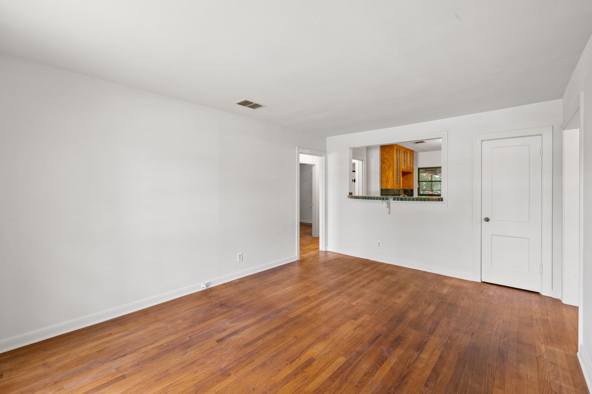 3704 Cherrywood Road Austin, TX 78722 - Photo 6 of 40 Original hardwood flooring stretches across this open living space, leading to a convenient kitchen pass-through bar.