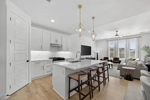 a open kitchen with stainless steel appliances granite countertop a sink a stove a dining table and chairs