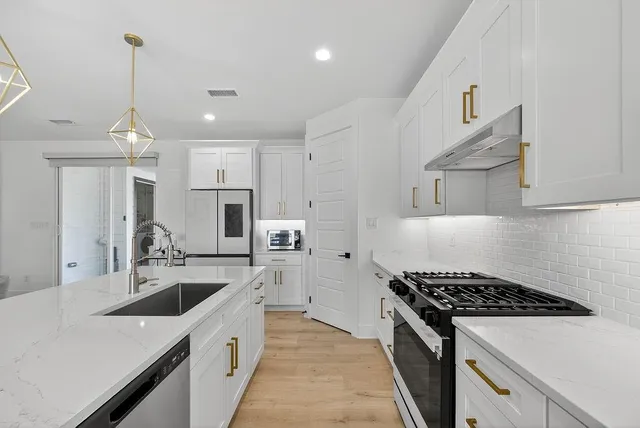 a kitchen with stainless steel appliances a sink a stove and a refrigerator